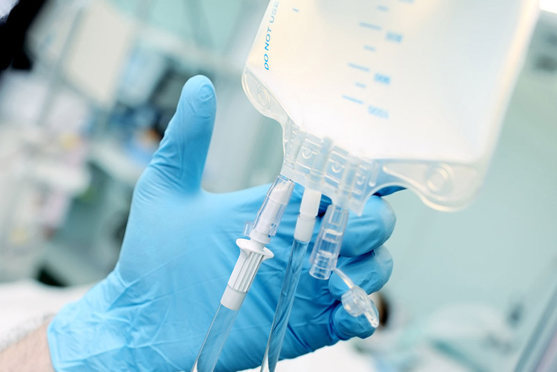 IV sedation guy holding IV wearing blue gloves